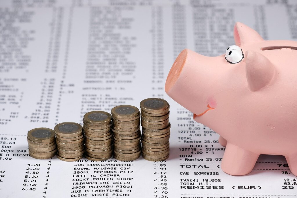 receipt in the background, coin piles and the side of a pig