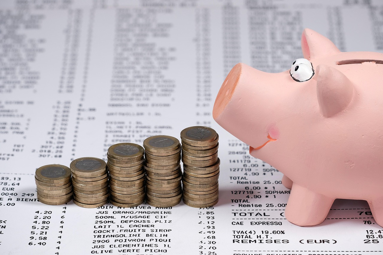 receipt in the background, coin piles and the side of a pig